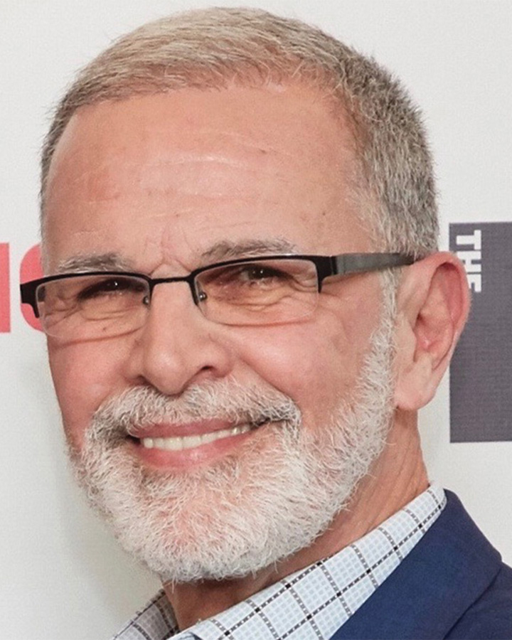 a head shot of a man with white hair and beard wearing glasses